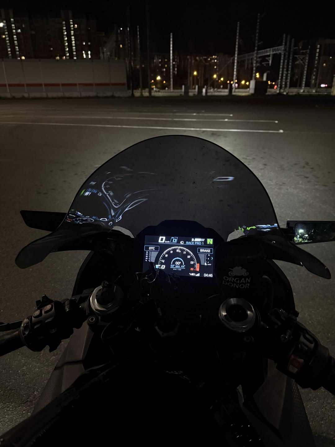 A motorcycle cockpit in a quiet parking lot at night